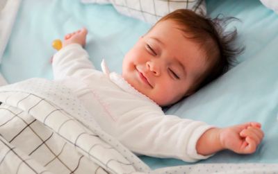 lille dreng der sover med sin babydyne og smiler