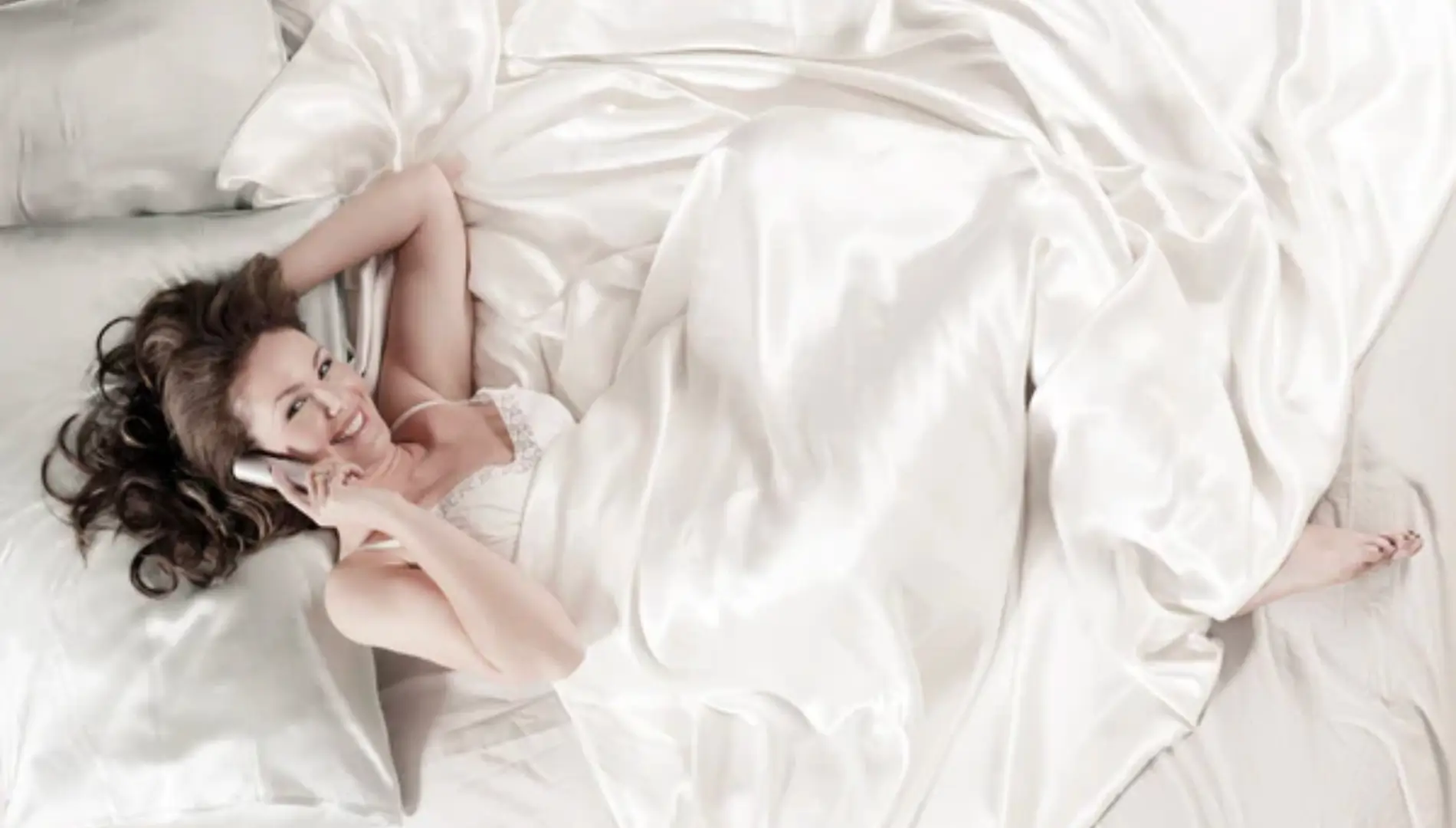 kvinde der ligger i sengen og nyder fordele ved en silkedyne